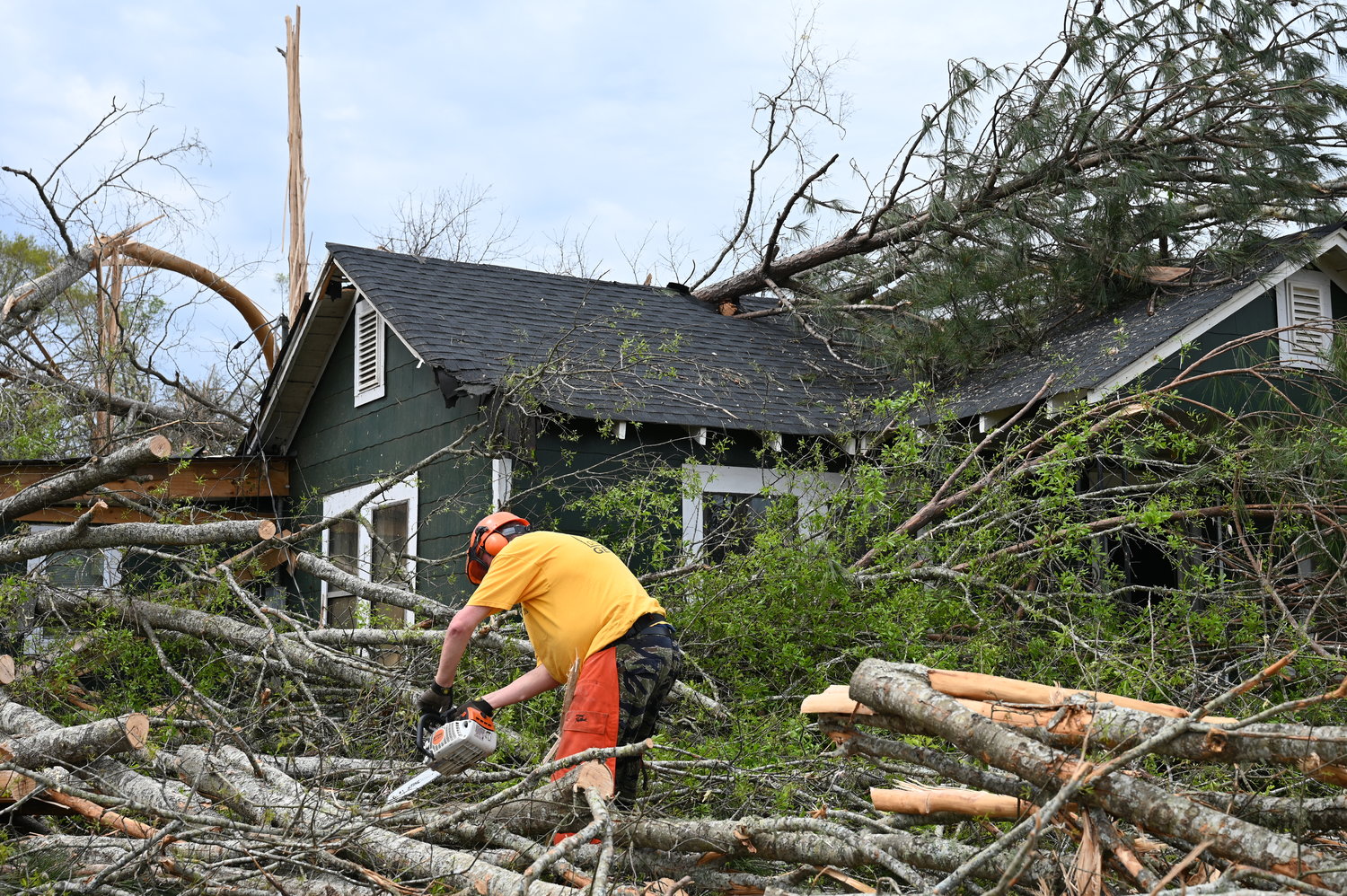 A Georgia Baptist Disaster Relief volunteer saws away down trees from a home in West Point, Ga., on Tuesday, March 28, 2023. (Index/Roger Alford)