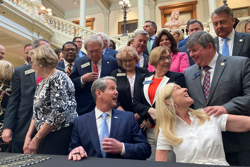 Georgia Gov. Brian Kemp, bottom center, speaks to state Sen. Larry Walker III, R-Perry, right, before signing bills into law at the state Capitol on Tuesday, May 2, 2023, in Atlanta. (AP Photo/Jeff Amy)