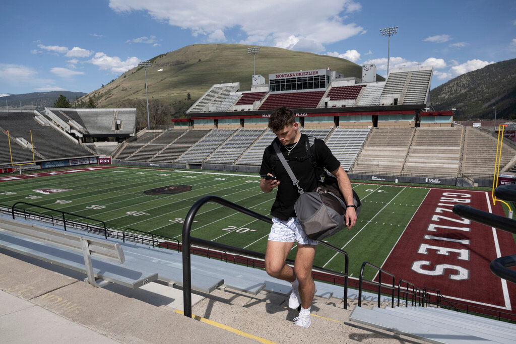 Adam Botkin, a football TikTok influencer, uses his phone after recording a video for a post at Washington-Grizzly Stadium in Missoula, Mont., on Monday, May 1, 2023. (AP Photo/Tommy Martino)