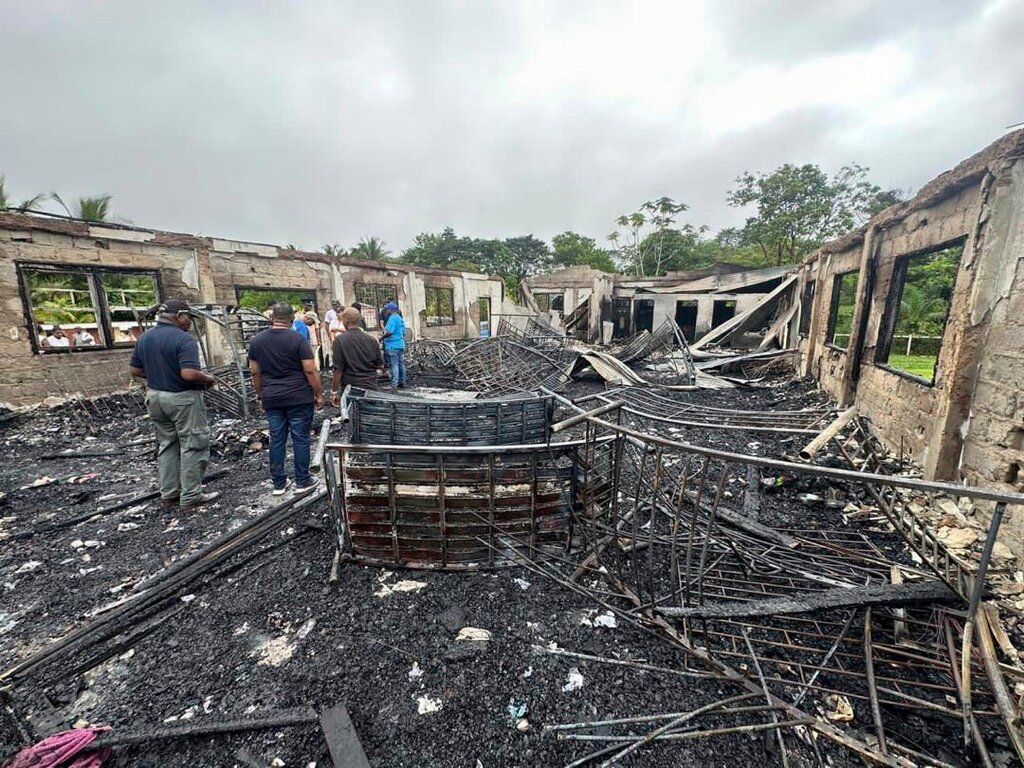 Investigators stand in a burned-out dormitory of a secondary school in Mahdia, Guyana, Monday, May 22, 2023. (Guyana's Department of Public Information via AP Photo)