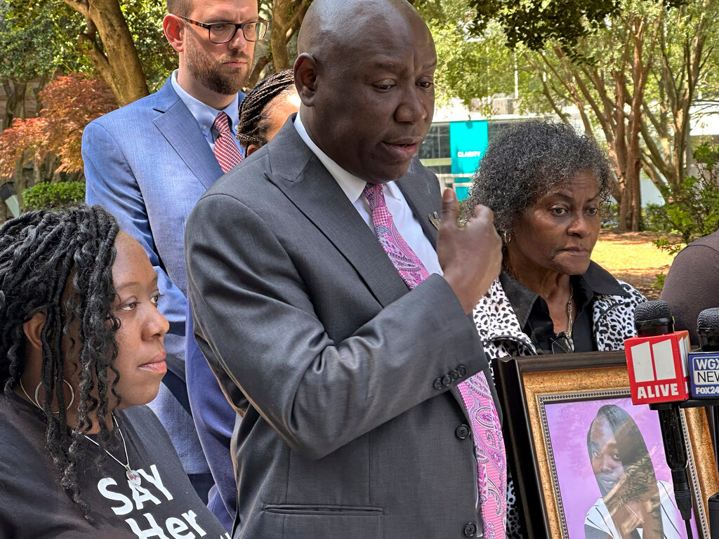 Prominent civil rights attorney Ben Crump speaks at a news conference on Wednesday, May 24, 2023, in Decatur, Ga., announcing a wrongful death lawsuit filed by the family of a Georgia woman who died after she fell out of a moving patrol car in July 2022, following her arrest. Crump was joined in front of the old courthouse in Decatur, by Brianna Grier's sister Lottie Grier, left, and mother Mary Grier, right. (AP Photo/Kate Brumback)