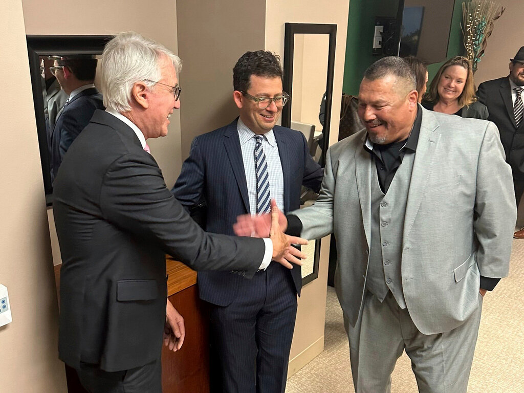 This undated photo, provided the by Los Angeles District Attorney's Office, shows Daniel Saldana, right, shaking hands with Los Angeles District Attorney George Gascon, left. Saldana's lawyer Mike Romano is in the middle. (Los Angeles County District Attorney's Office via AP)