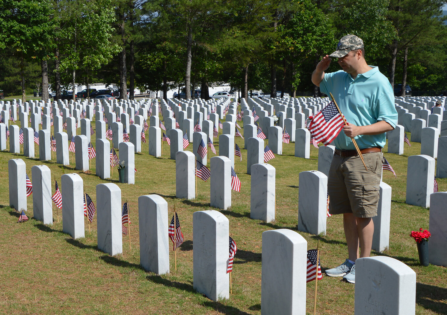 Nick Carter, himself a veteran, salutes after placing a flag on a grave at the Georgia National Cemetery in Canton, Ga., Saturday, May 27, 2023. (Index/Henry Durand)