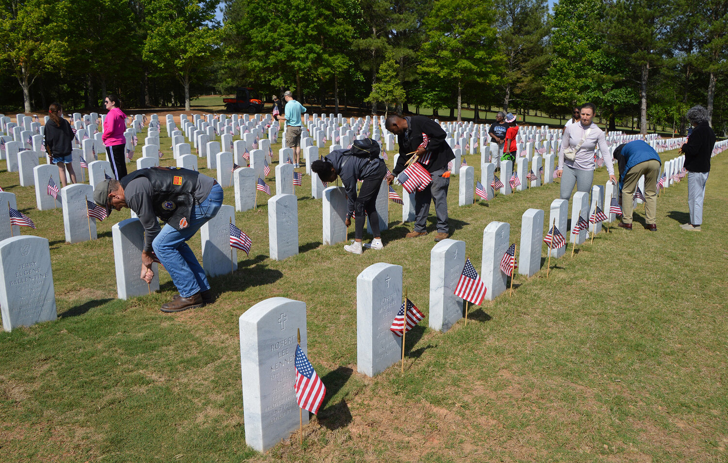 Volunteers place flags on graves at the Georgia National Cemetery in Canton, Ga., Saturday, May 27, 2023. (Index/Henry Durand)