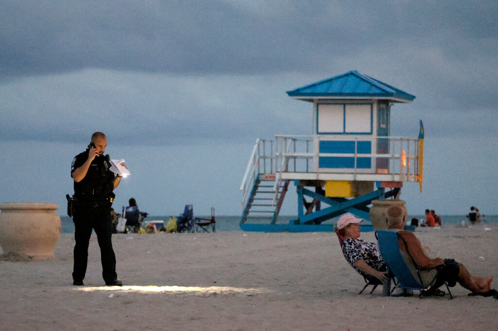 A police officer shines his flashlight on Hollywood Beach while investigating a shooting Monday, May 29, 2023, in Hollywood, Fla. (Mike Stocker/South Florida Sun-Sentinel via AP)