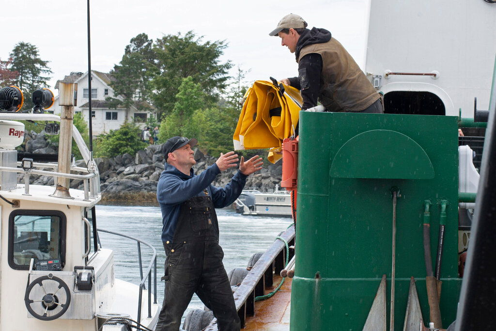Lee Hanson, left, and Ryan Martin of Hanson Maritime Company transfer float bags and other boat salvage equipment from the tugboat Salvation to a smaller boat at Crescent Harbor in Sitka, Alaska, on Wednesday, May 31, 2023. (James Poulson/Daily Sitka Sentinel via AP)