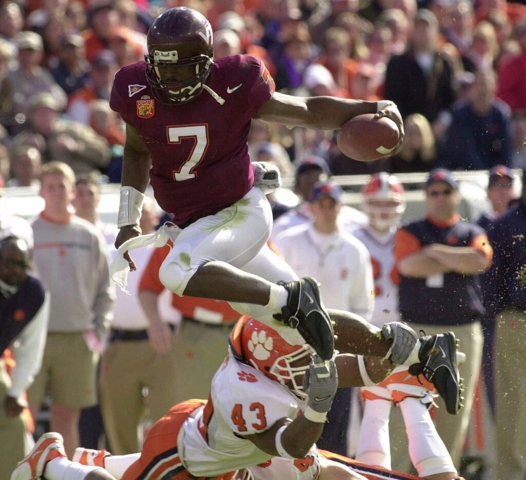 Virginia Tech quarterback Michael Vick (7) eludes Clemson's Keith Adams for a short gain in the first quarter of the Gator Bowl in Jacksonville, Fla., Jan. 1, 2001. (AP Photo/Steve Helber, File)