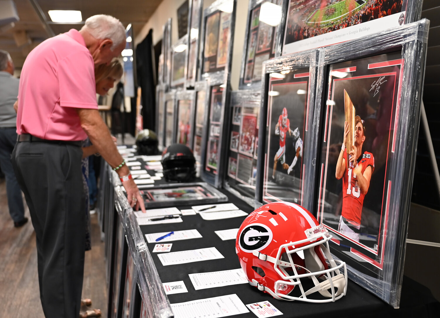 Rudy and Diane Maul look at sports memorabilia during a silent auction to raise money for the Fellowship of Christian Athletes at the UGA Night of Champions event on Friday at First Baptist Church of Woodstock. (Index/Henry Durand)