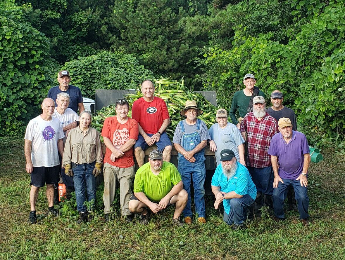 Volunteers pose after picking corn in the July sun.