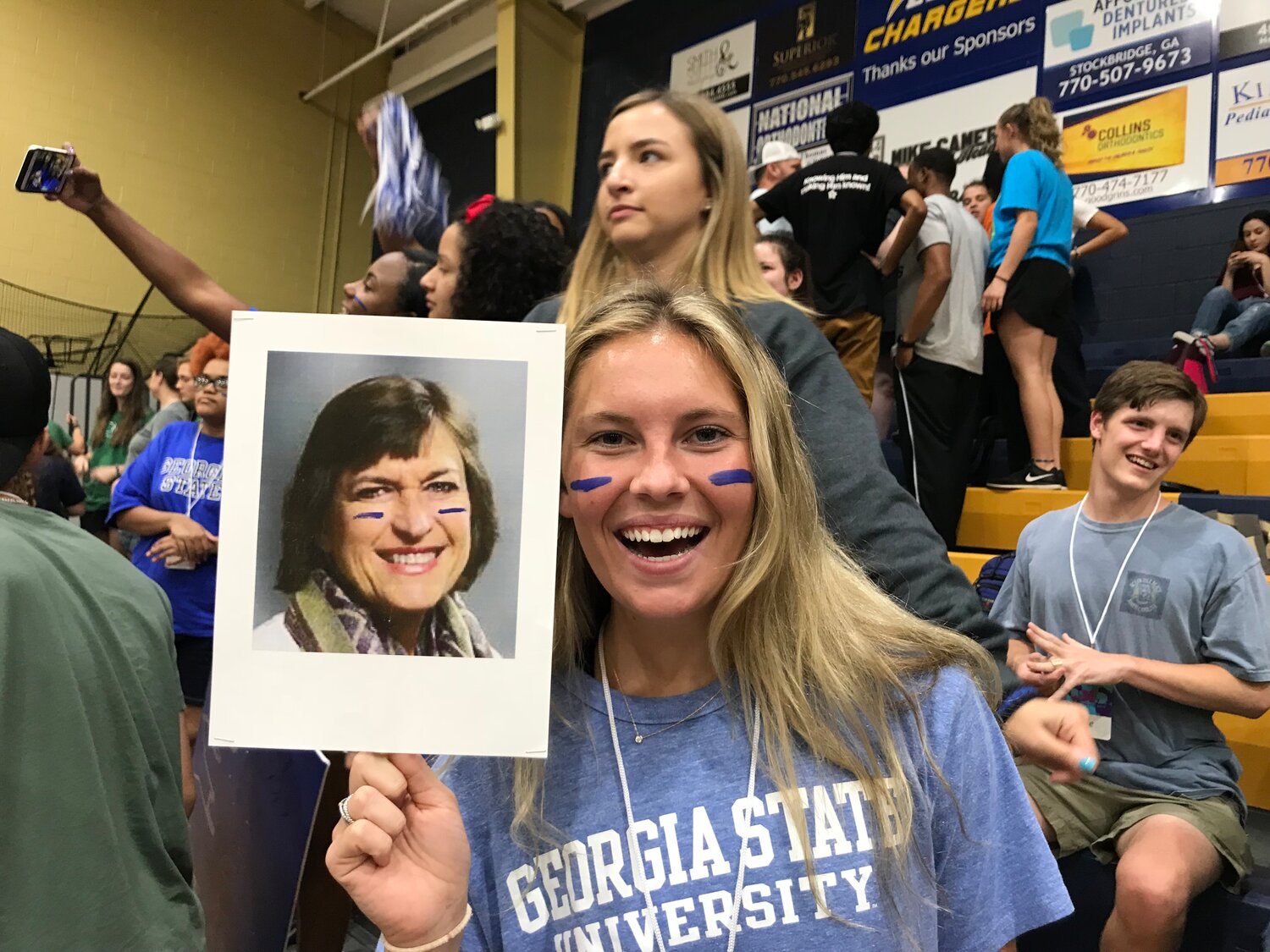 Anna Grace Davis holds a photo of Teresa Royall at a Baptist student event. Royall, the legendary campus ministry director at Georgia State University, is retiring. (Photo/Baptist Collegiate Ministries)