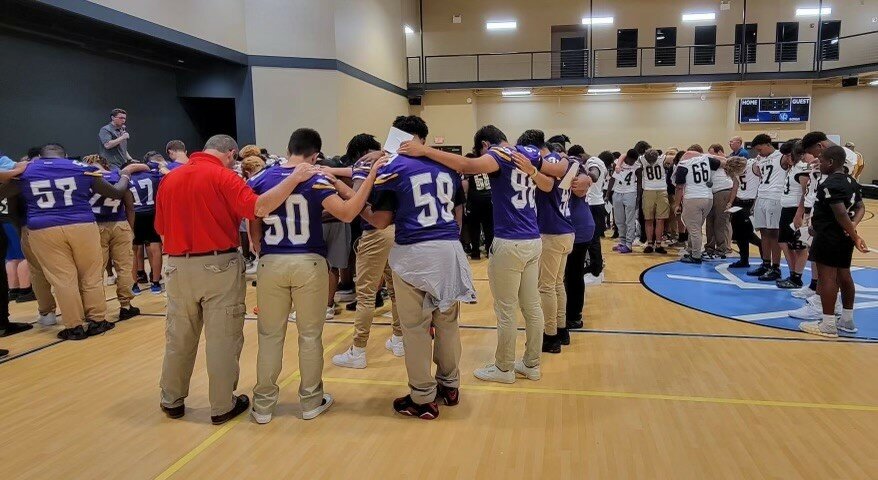 Student athletes pray together during Gridiron Day, an event that's built around the gospel.
