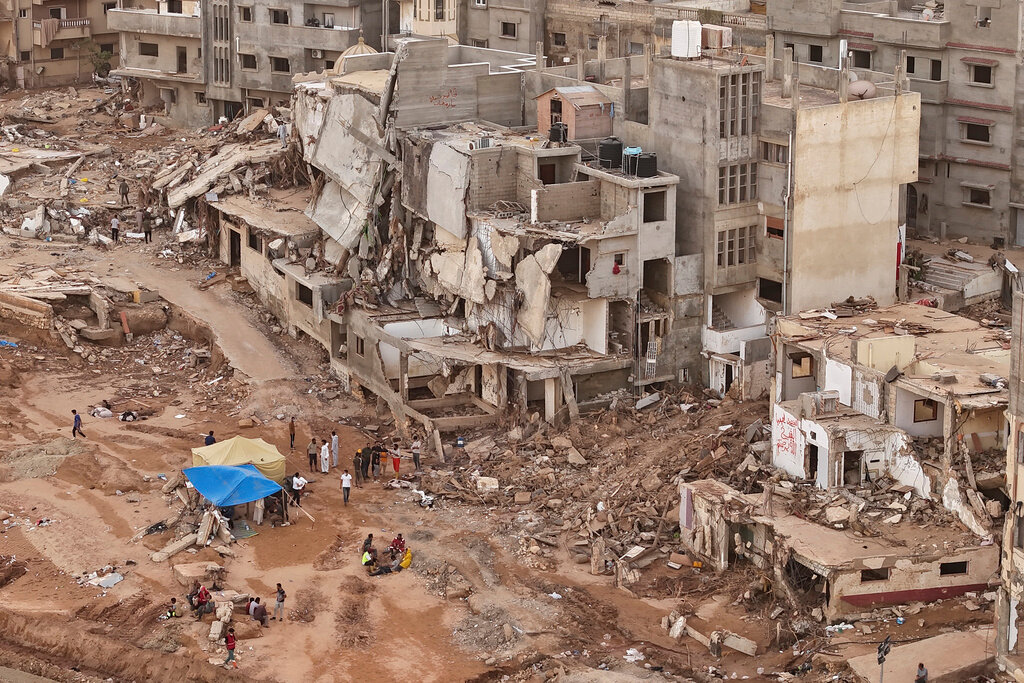 Rescuers and relatives of victims set up tents in front of collapsed buildings in Derna, Libya, Monday, Sept. 18, 2023. (AP Photo/Muhammad J. Elalwany)