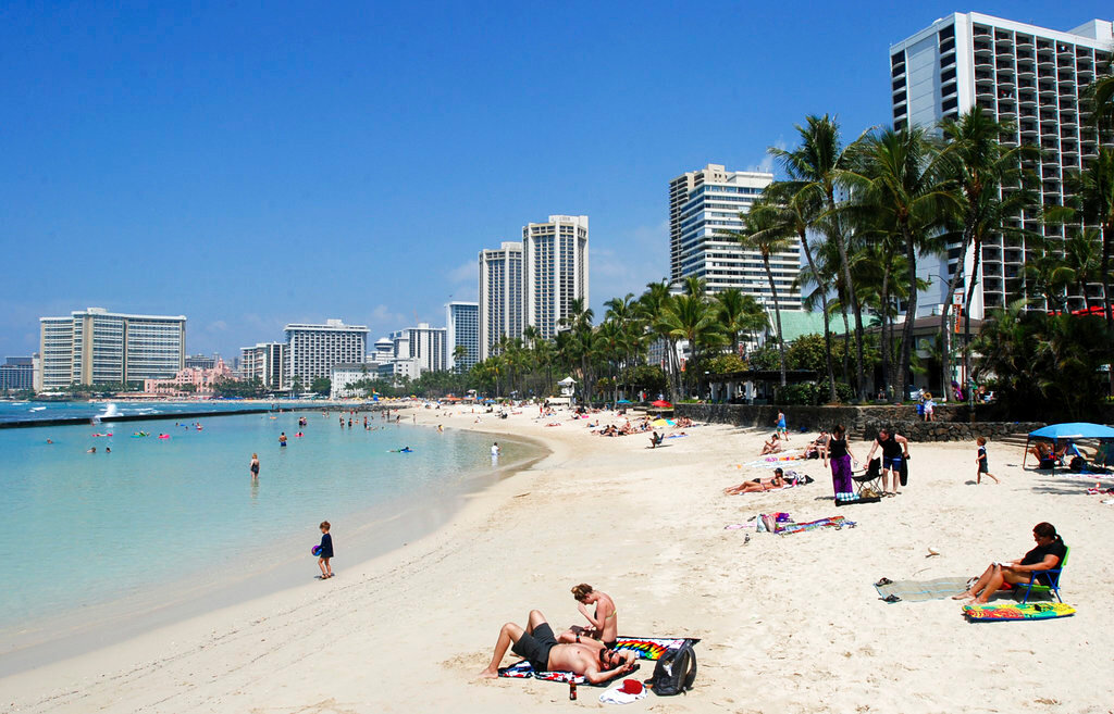 People relax on the beach in Waikiki on March 13, 2017 in Honolulu. (AP Photo/Caleb Jones, File)