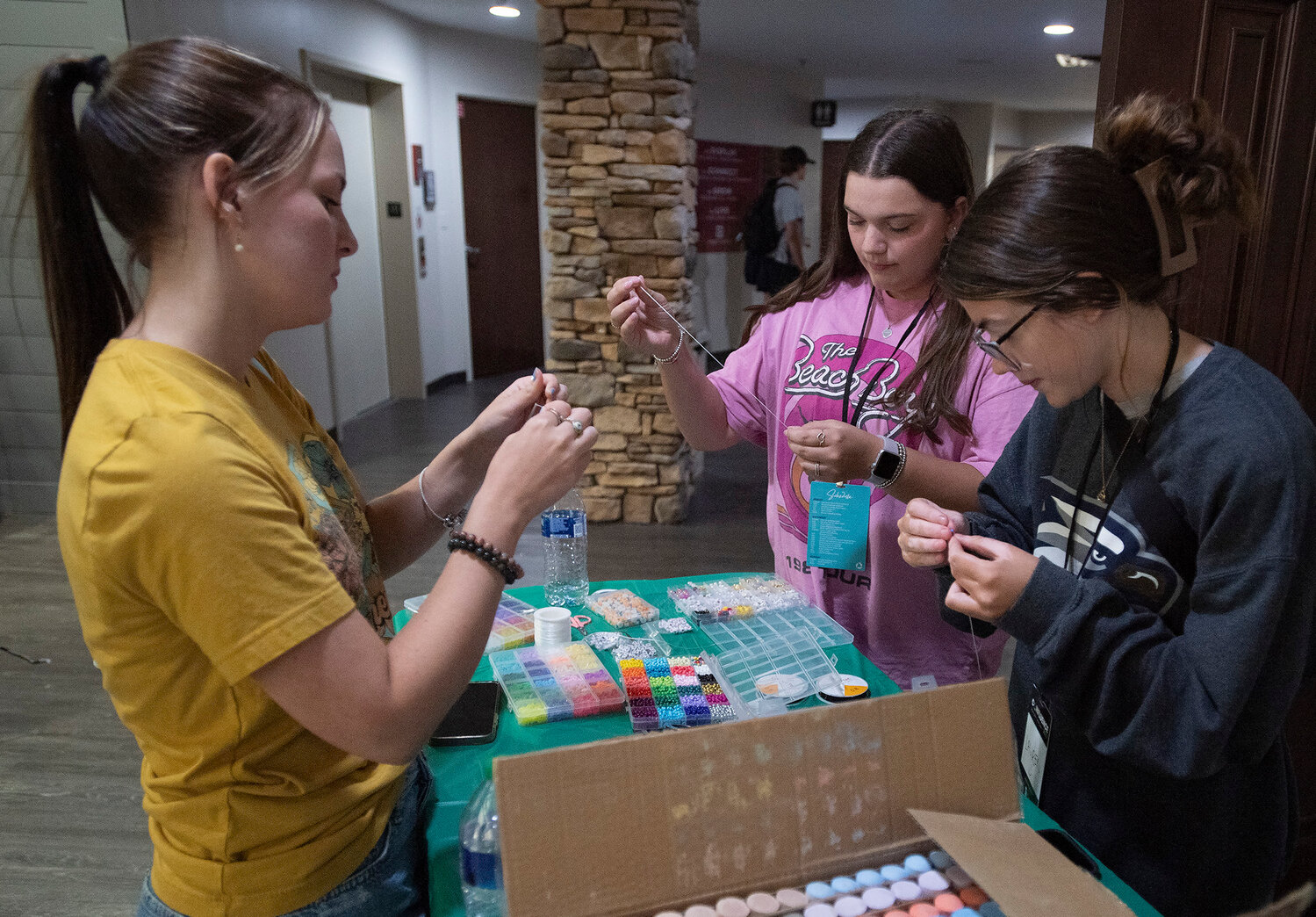 Ansley Vickers, Kayla Maddox and Lauren Richardson, from left, make friendship bracelets during Confluence 2023 at Eagle's Landing First Baptist Church in McDonough, Ga., Saturday, Sept. 23, 2023. The three attend Georgia Southern - Armstrong. (Index/Henry Durand)