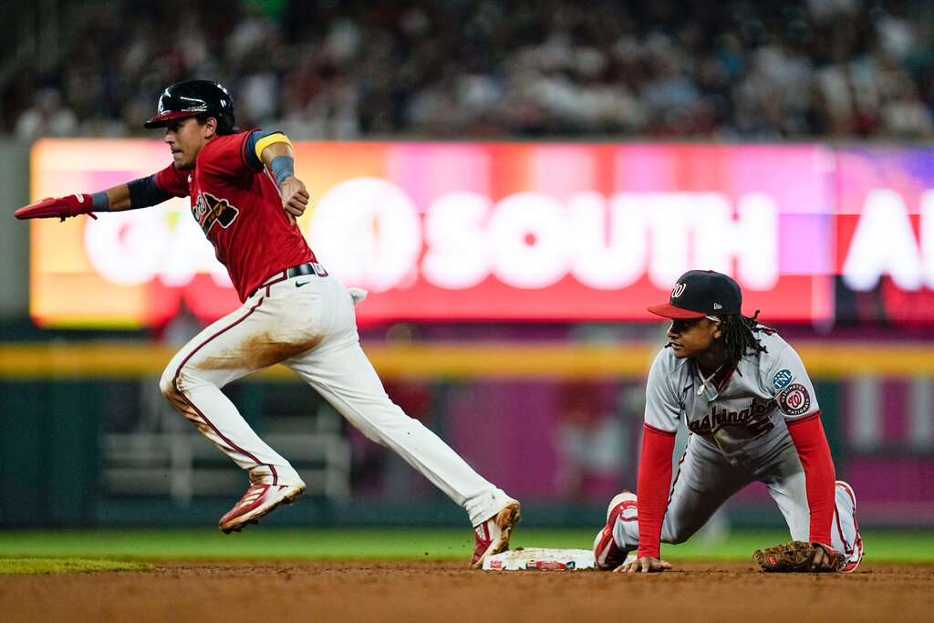 Atlanta Braves' Nicky Lopez runs to third past Washington Nationals shortstop CJ Abrams, right, on a hit by Braves' Eddie Rosario during the fifth inning Friday, Sept. 29, 2023, in Atlanta. (AP Photo/Mike Stewart)