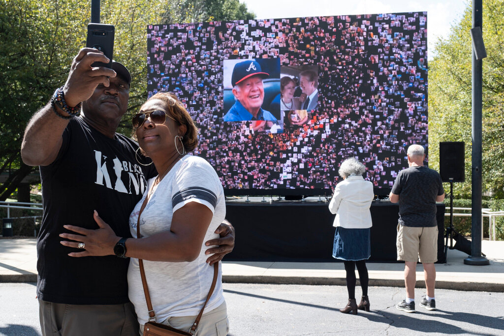 Kevin and Ursula Jones take a photo together in front of a video screen while attending the celebration for President Jimmy Carter's 99th birthday held at The Carter Center in Atlanta on Saturday, Sept. 30, 2023. (AP Photo/Ben Gray)