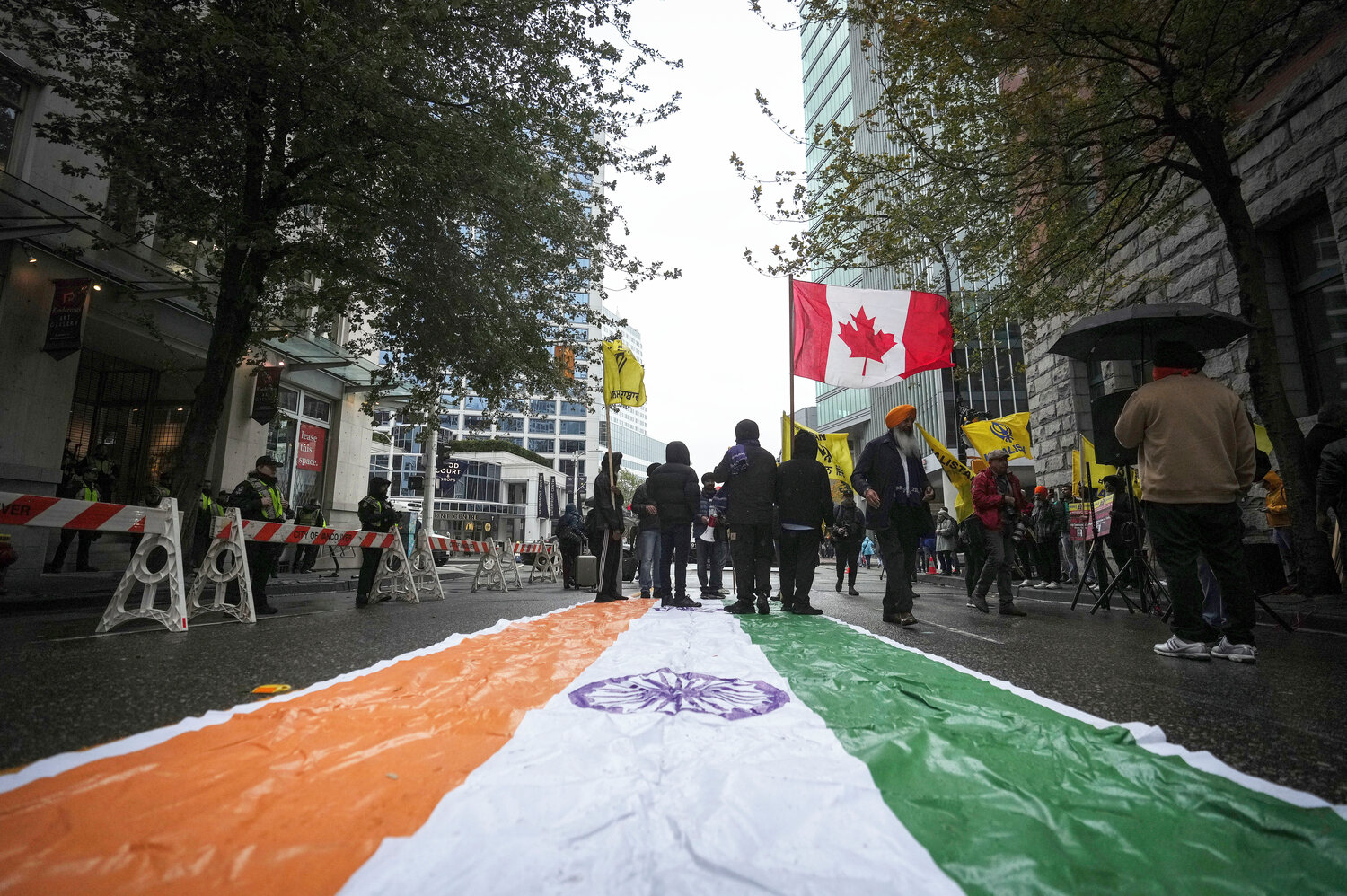 An Indian flag is laid on the street as protesters wave a Canadian and Khalistan flags during a protest outside the Indian Consulate in Vancouver, British Columbia, on Monday, Sept. 25, 2023. (Darryl Dyck/The Canadian Press via AP)