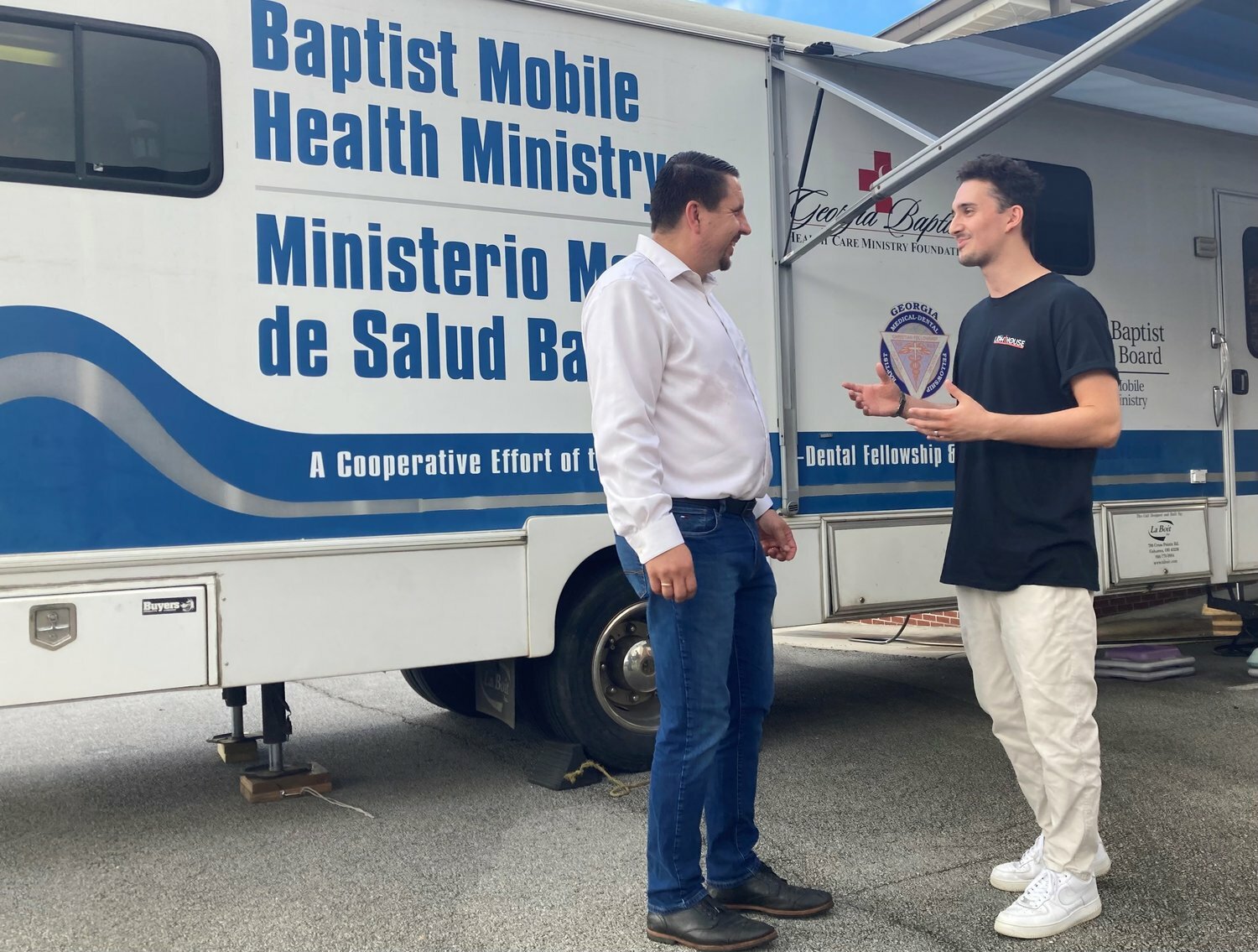 Lighthouse Church Pastor Max Lisovskiy, left, talks with Andrii Bradarskyi, outside a Georgia Baptist mobile dental clinic.