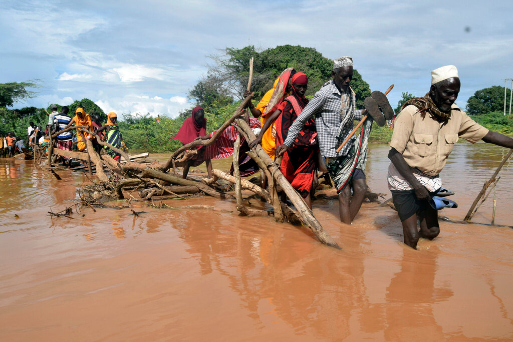 Residents of Chamwana Muma village walk through flood water after using a makeshift bridge to cross the swollen River Tana, in Tana Delta, Kenya, on Wednesday Nov. 15, 2023. Unrelenting rainfall across Kenya's northern counties and the capital, Nairobi, has led to widespread flooding, displacing an estimated 36,000 people and killing 46 people since the beginning of the rainy season less than a month ago. (AP Photo/Gideon Maundu)