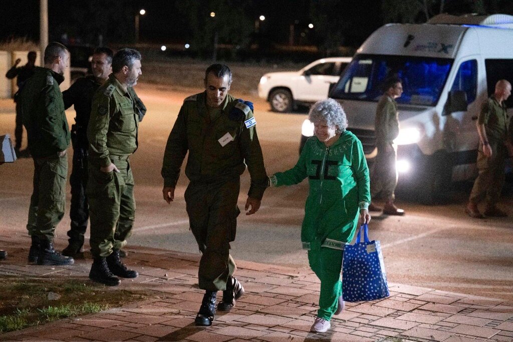 Ruth Munder, a released Israeli hostage, walks with an Israeli soldier shortly after her arrival in Israel on Friday, Nov. 24, 2023. (IDF via AP)