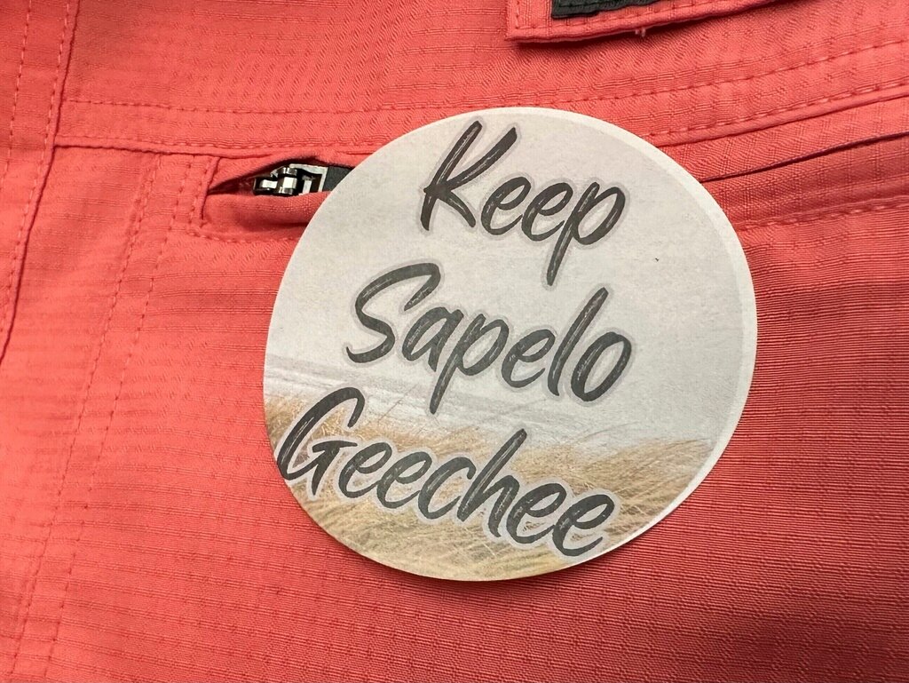 A sticker saying "Keep Sapelo Geechee" is worn on the shirt of George Grovner, a resident of the Hogg Hummock community on Sapelo Island, during a meeting of McIntosh County commissioners, Sept. 12, 2023, in Darien, Ga. (AP Photo/Ross Bynum, File)