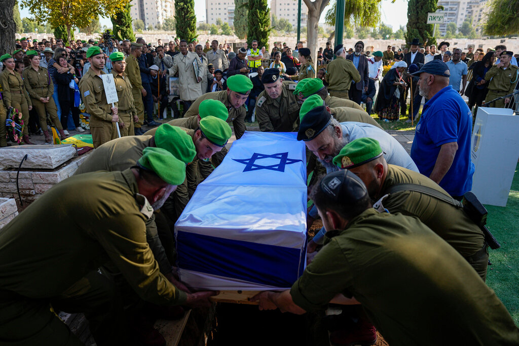 Israeli soldiers lower into the grave the flagged coffin of Staff Sergeant Aschalwu Sama during his funeral in Petah Tikva, Israel, Sunday, Dec. 3, 2023. Sama, 20, died of his wounds after he was injured in a ground operation in the Gaza Strip. (AP Photo/Ariel Schalit)