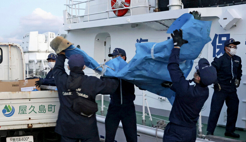 Members of the Japanese Coast Guard carry debris believed to be from a crashed U.S. military Osprey aircraft, at a port in Yakushima, southern Japan, Monday, Dec. 4, 2023. (Kyodo News via AP)