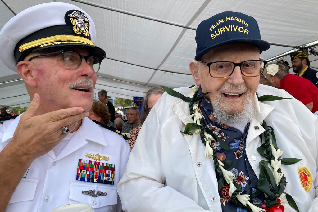 Ira Schab, right, who survived the attack on Pearl Harbor as a sailor on the USS Dobbin, talks with reporters while sitting next to his son, retired Navy Cmdr. Karl Schab, on Dec. 7, 2022, in Pearl Harbor, Hawaii. (AP Photo/Audrey McAvoy, File)