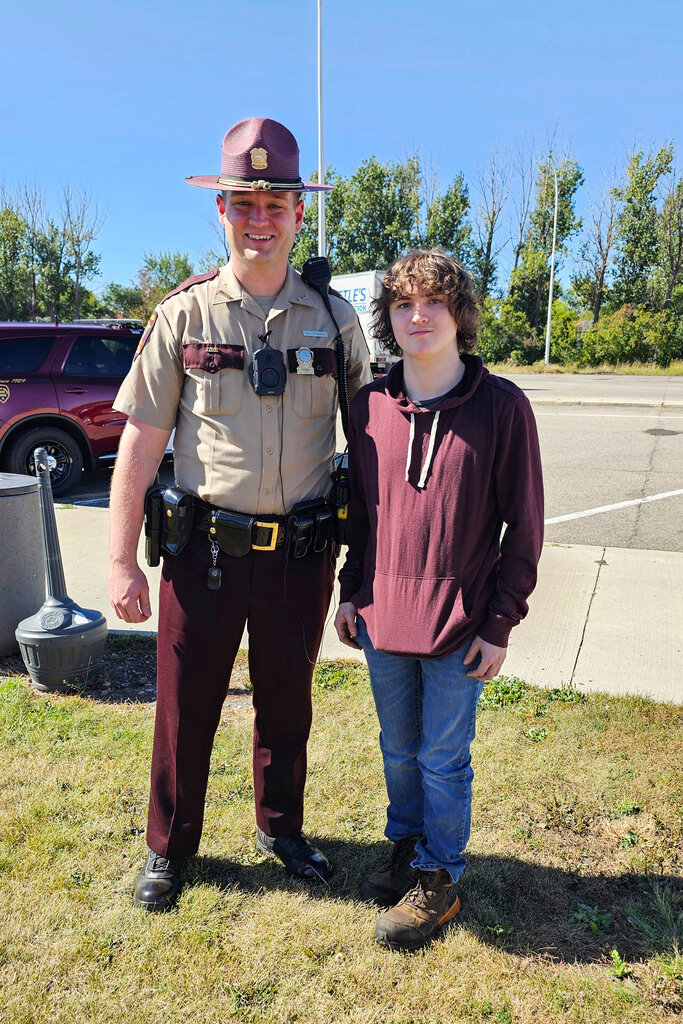 This photo provided by Catherine Dutcher shows Sam Dutcher with Minnesota State Patrol Trooper Zach Gruver at the Travel Center in Moorhead, Minn., Wednesday, Sept. 25, 2024. (Catherine Dutcher via AP)