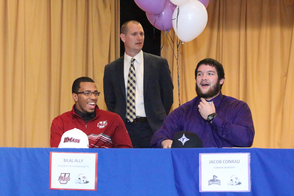 Clay signees  Clay High running back Bilal Ally, left, smiles with offensive lineman Jacob Conrad as coach Joshua Hoekstra introduces the pair at the February 3 National Signing Day ceremonies at Clay High School. Clay signed seven scholarships with Ally heading to the University of Massachusetts and Conrad going to Furman University.