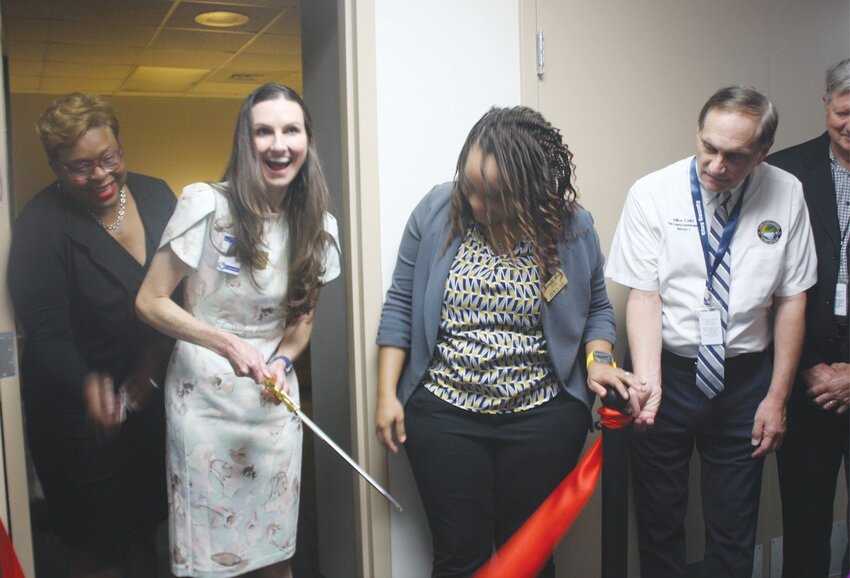 Kelli Lueckert, Assistant County Attorney and immediate past president of Jacksonville Women Lawyers Association, smiles as she cuts the ribbon for a nursing lounge at the courthouse while Kimberly Woods, current president of the organization and Commissioner Mike Cella watch in approval.
