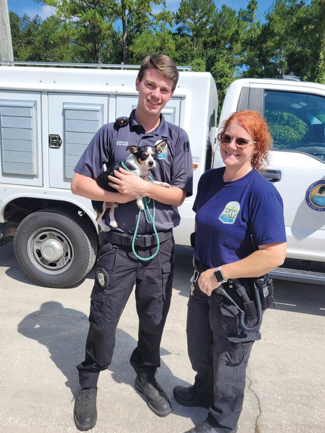 Animal control officer Kaleb Varady and Kelly Minix pose with Tiny Tim, who was trapped inside an air conditioner in Orange Park.