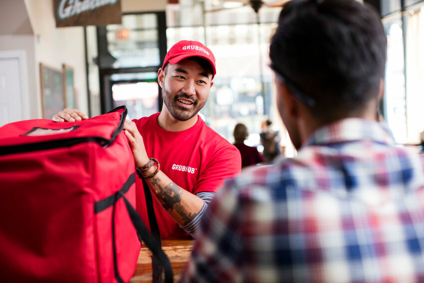 A Grubhub deliveryman is picking up an order from a restaurant. The Grubhub corporation supported the proposed legislation.
