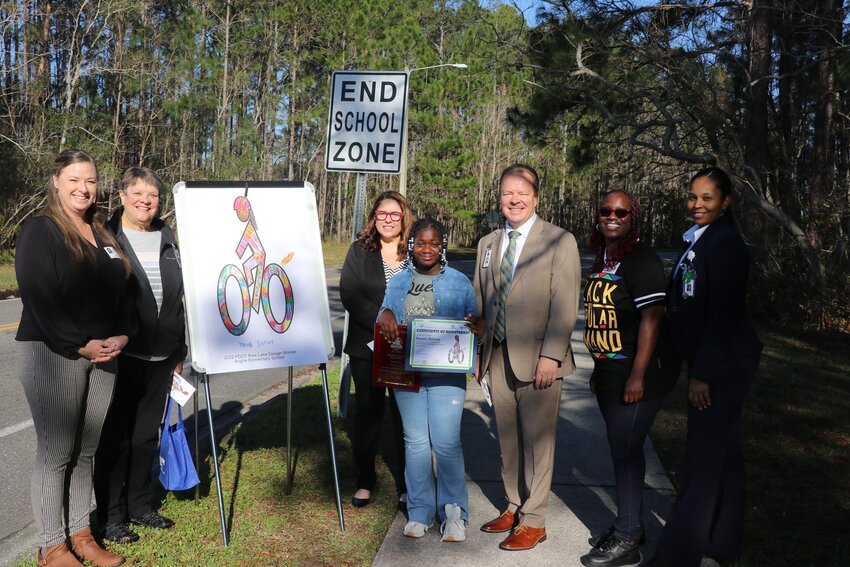Naomi Dorsey stands next to her creation with her family, school and district officials.