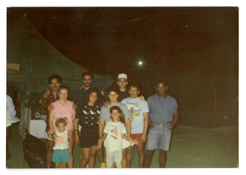 The 10 passengers who traveled on the boat made by Celia's father have since lost touch after arriving in Guantanamo. Celia is standing in the front with the American flag shirt. Evelyn and both her parents stand just behind her. The man in the white baseball camp regretfully dropped the compass. All 10 passengers eventually found entry into the U.S.