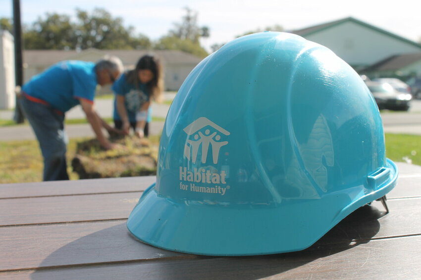 Volunteers in the background help spread sod for the 182nd and 183rd houses built by Clay County Habitat for Humanity.