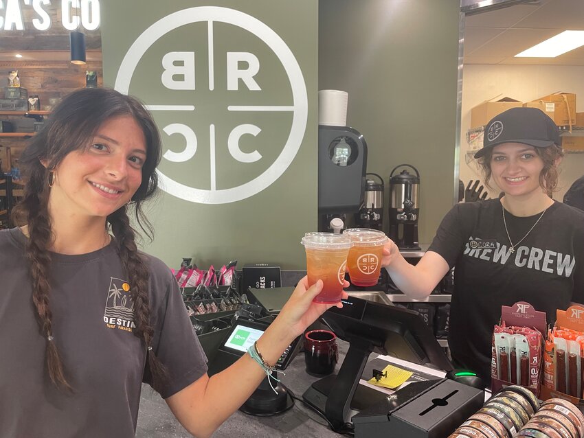 Baristas Alexa, left, and Cora clink glasses of Parachute Punch.