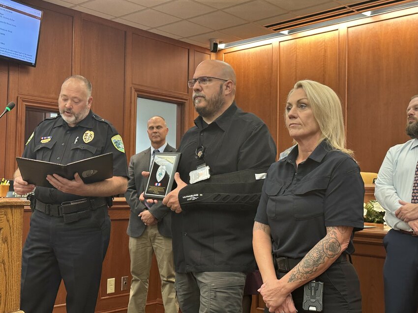 Green Cove Springs Interim Police Chief Shawn Hines, left, reads a proclamation honoring Sgt. Chris Hess with the Medal of Merit for his diligence and compassion after a man died after being hit and dragged by a train.