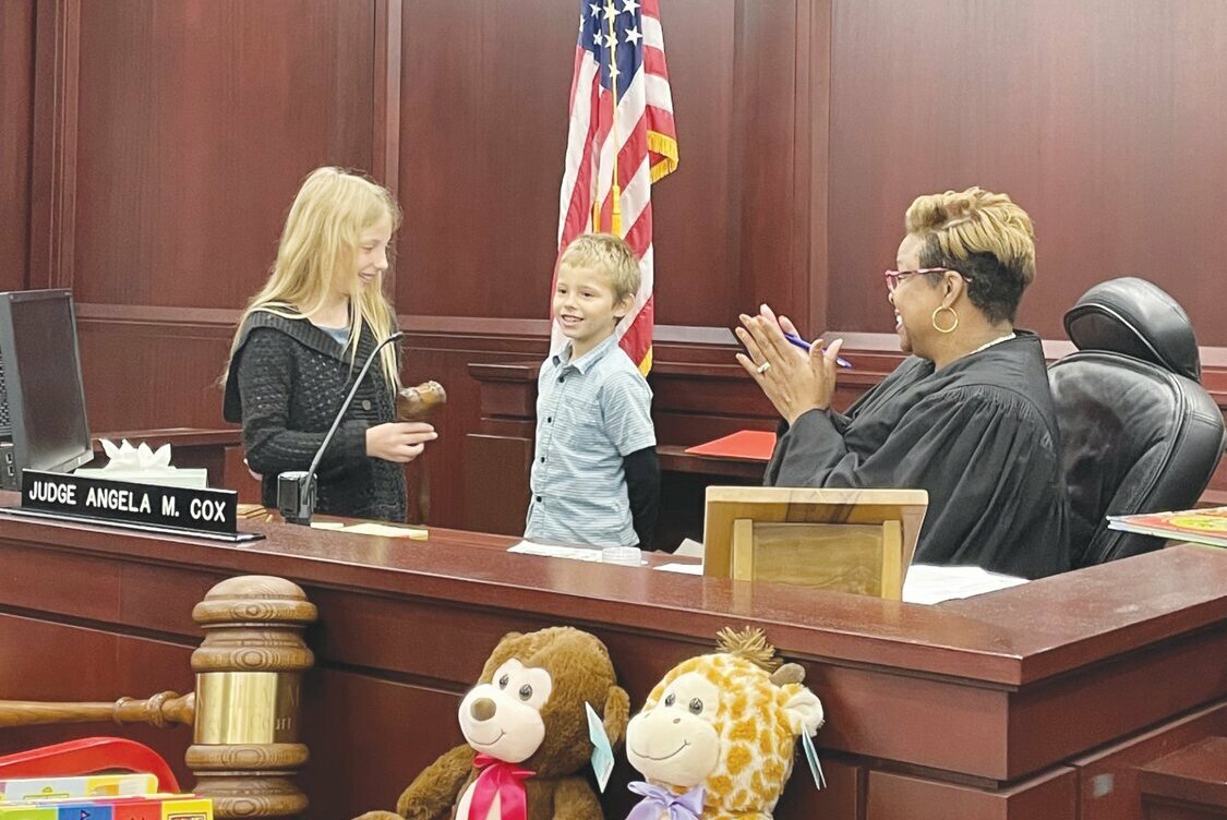 Judge Angela Cox invited Reyana (left) and Tristan (right) to hammer the gavel to finalize their adoptions. Afterward, they were invited to pick out a book and a stuffed animal to take home.