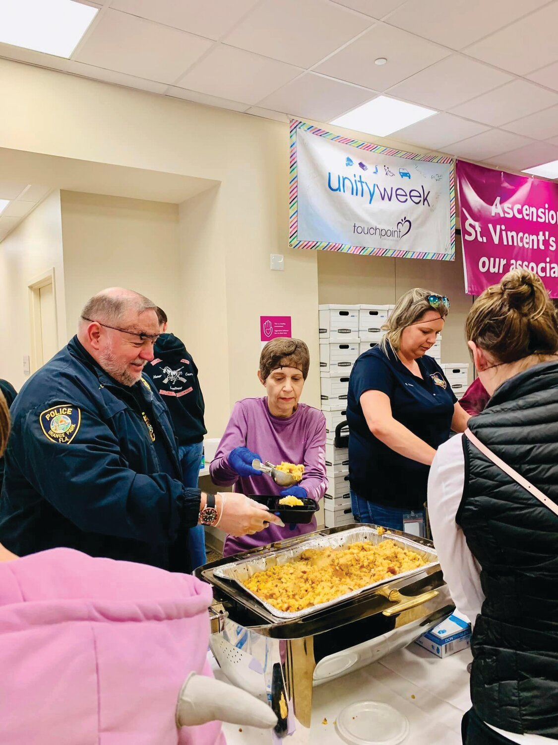 Orange Park PD Assistant Chief Randy Case helps fill food boxes while members of the Orange Park Police Department and Clay County Sheriff’s Office load cars for deliveries to seniors.