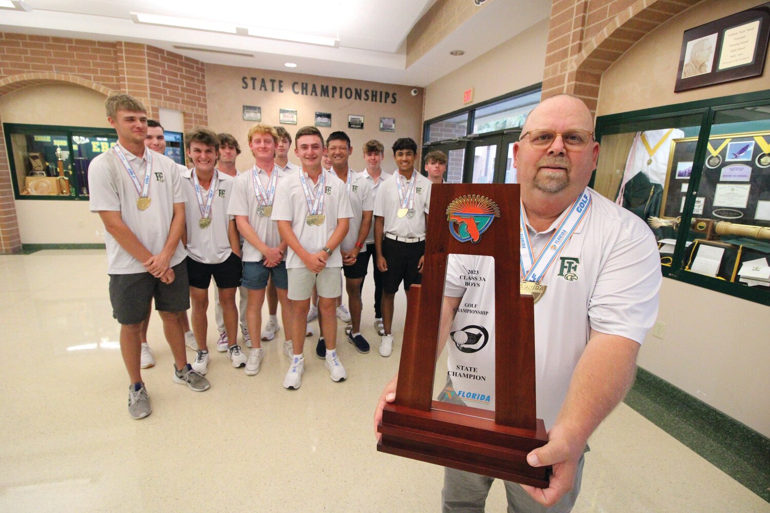 Fleming Island High boys golf team coach Bruce Cloud holds up his Class 3A trophy with his team behind him including sophomore Tyler Mawhinney. Mawhinney, the Class 3A individual champion, and Cloud were named Dairy Farmer golf player of the year and coach of the year.