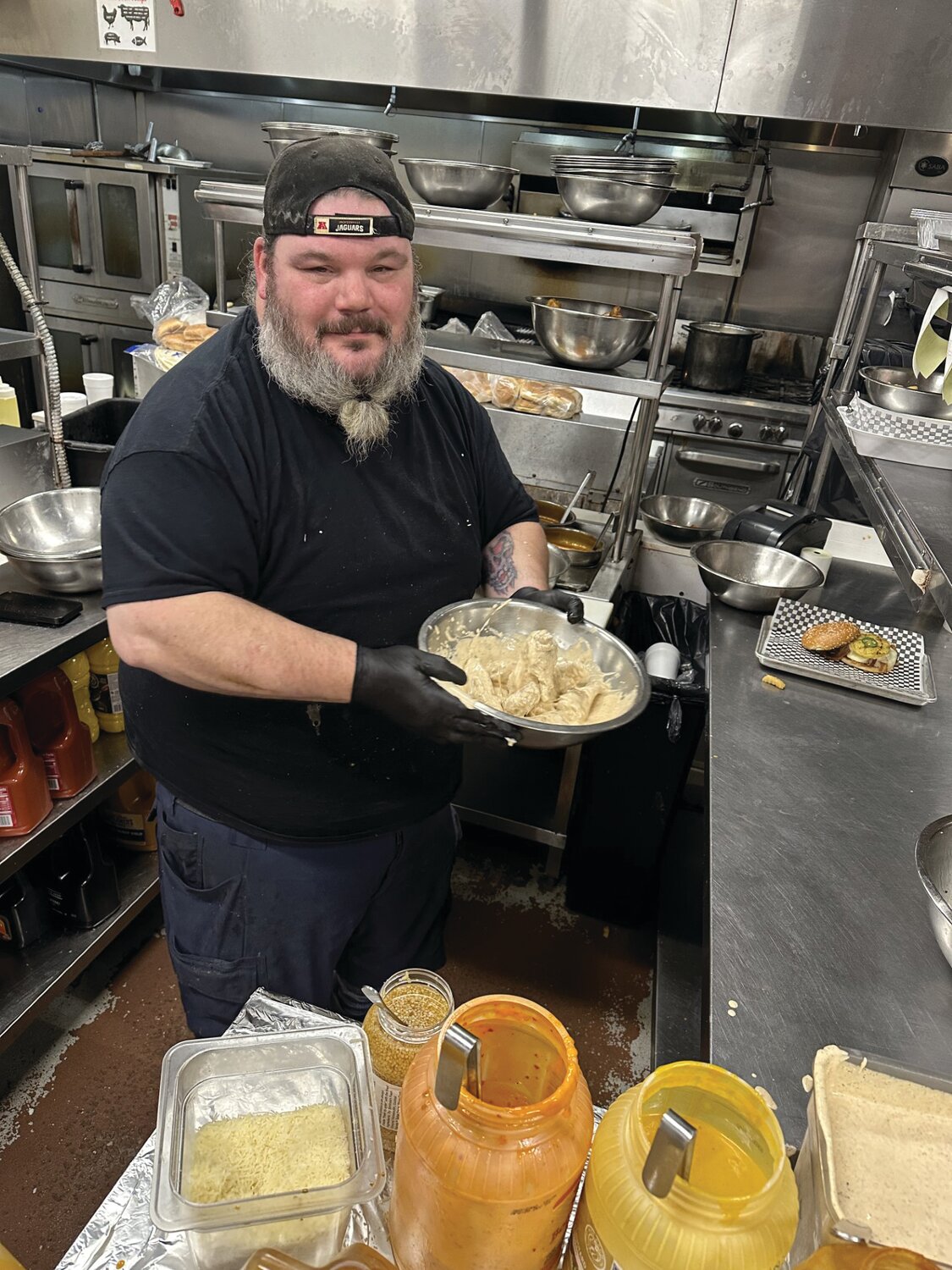 Kitchen manager Todd Phillips tosses Dalton’s homemade Cajun Ranch sauce to an order of wings