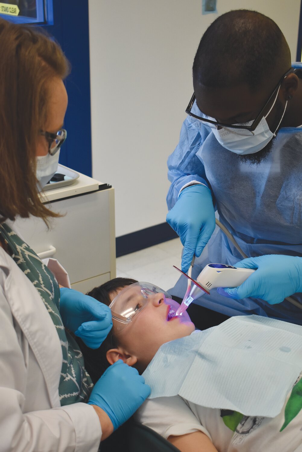 Program Director Christine Eason (left) and student Frederick Campbell used an LED curing light on Liam’s filing. The light helps the dental resin harden in less than 60 seconds.