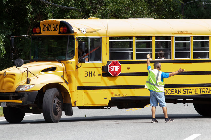 A crossing guard in front of Hampden Meadows School stops traffic to let a bus exit.  of the town council are considering installing speed cameras along New Meadow Road in front of HMS.