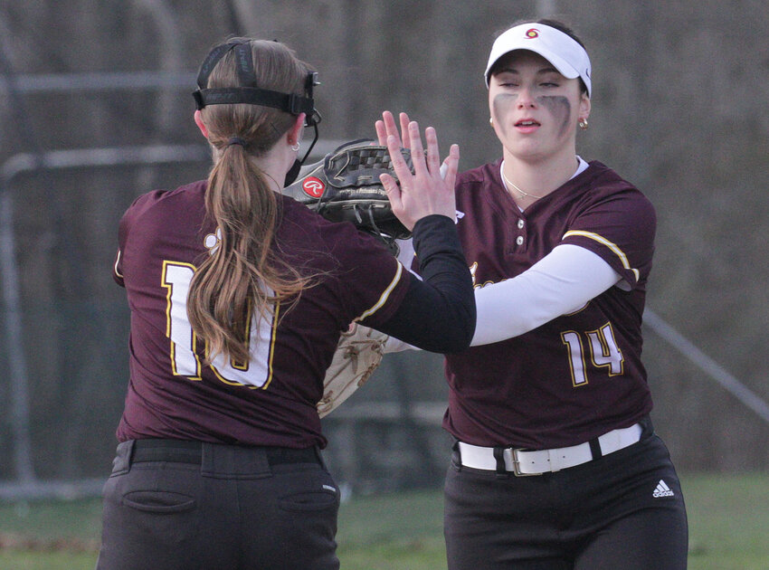 First baseman Carlie Martin (left) high fives second baseman Sara Poland after she caught an infield fly to end the game. 
