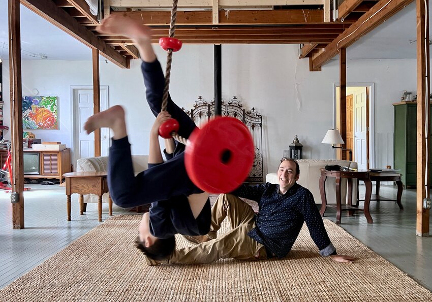 Brian Moses looks on as son Gryffin, 8, plays on his swing in the family's living room.