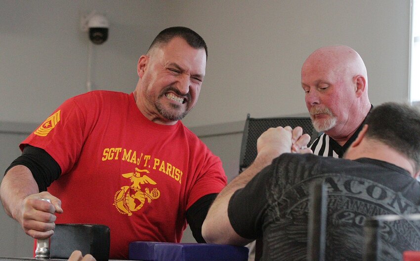 Chris Burns (facing camera) attempts to slow down powerful Maine arm-wrestler Kurt Howgate during their match, with referee Bill Caldwell looking on. Howgate and Burns took first and second place, respectively, in both the open left-hand heavyweight/super division, and the open right-hand super heavyweight division.
