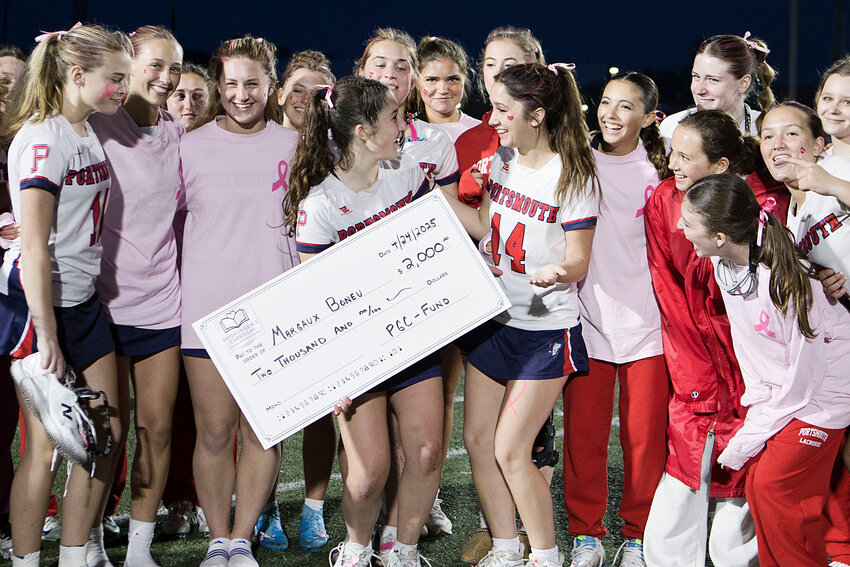 Portsmouth High lacrosse players Margaux Boneu (left) and Addison Lima react with their teammates after Margaux was awarded a scholarship in honor of her late mother, Patricia Grace Carellas, during a match against Prout on Friday. Carellas passed away in December of breast cancer and the the lacrosse team raised awareness and funds for breast cancer research during the game.