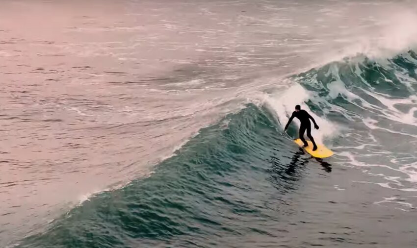 A surfer catches a wave in Little Compton, in a still taken from video