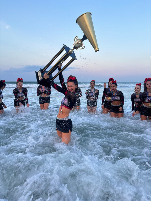 Barrington’s Kaleigh Moran holds the NCA All Girl D-1 National Championship trophy as the Northeastern University cheer team celebrates its national title at the beach in Daytona, Fla.
